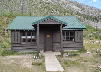 Brown wood cabin with green roof in a burned over forest