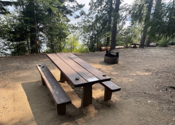 A picnic table and fire ring at a campsite on Priest Lake