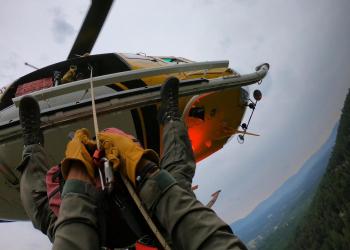 One person exits hovering helicopter via rappel cable