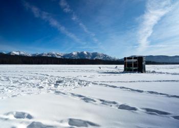 Image of and ice fishing shack on Seeley Lake in wintertime, Lolo National Forest, Montana.