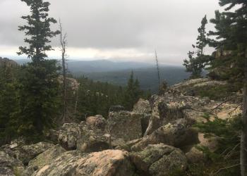 Image of clouds over distant peaks with a rocky slope in the foreground