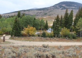 Image of a road with a small picnic ground in the back. Includes trees and a far away mountain.