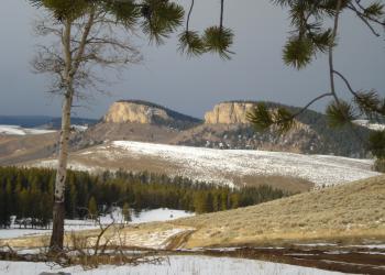 Image of two buttes with snow and trees in the forground