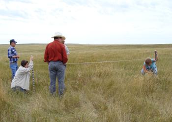 Two people read Robel poles while three others observe.