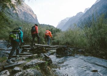 a group of hikers walk across a stream