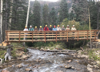 Group of people pose on a bridge in a forest.