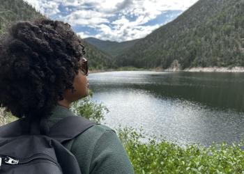 A woman looks over an alpine lake.