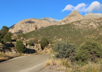 A road points towards rocky mountain faces