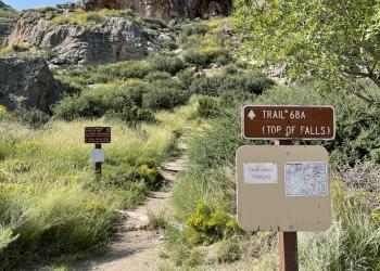 a rock trail with a sign and map next to it