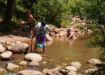 Three kids play in a low-flowing creek in Payson at Tonto Creek Campground.