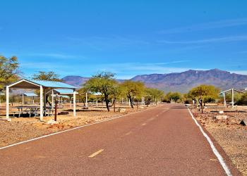 Photo shows picnic tables and shade covers at Schoolhouse Campground Site.