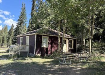 A side view of the Big Flat Guard Station Cabin, displaying a picnic table and rest area