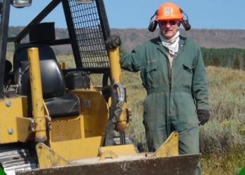 Volunteer Stan Adams is shown next to road maintenance equipment which he uses to lend his time and expertise as a trail dozer operator on the Fishlake National Forest motorized trails.
