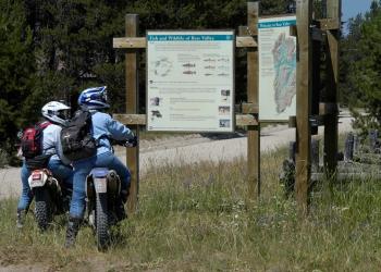 OHV motorcyclists reading forest kiosk