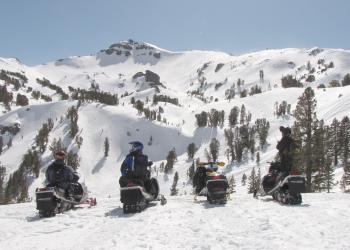Scenic picture of 4 snowmobiles in the BWRA with snow and mountains.
