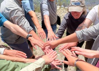 Partners, Forest Service Staff, and volunteers put hands together at training.