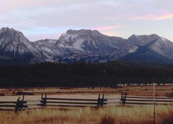 A large mountain range with a log fence in front