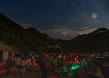 astronomers with telescopes set up to teach visitors how to use them and view the stars and planets