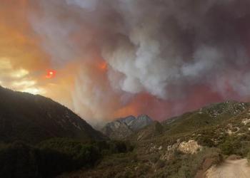 Gray smoke billows over mountainous terraine