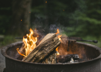 A burning campfire within a steel ring at a campground.
