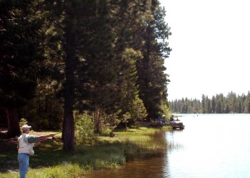 A man casting his fishing line into a lake. 