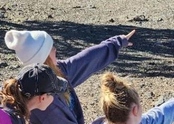 Students pointing to far off mountains in a map orienting course