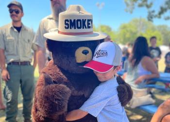 A child hugging Smokey Bear at an event