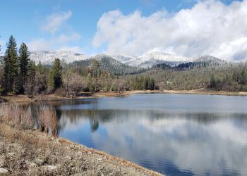A lake is visible in the foreground with snowy mountains in the distance.