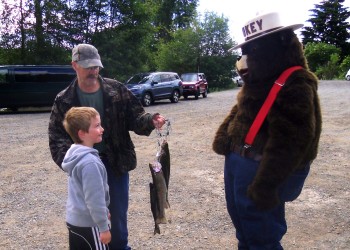 Fisherman and child show-off catch, to Smokey Bear