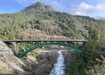 Green bridge over running water in mountainous area 