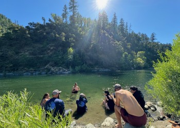 Group of people sunbathing and relaxing in and next to river