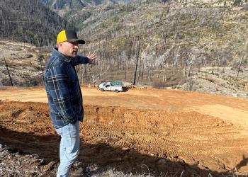 a man points at a construction site on a forest service road