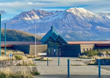 This image shows a snowy Mount St Helens behind the Science and Learning Center at Coldwater. 