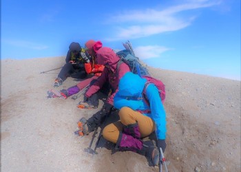 Climbers getting ash blown into their faces at summit of mountain