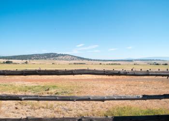 A close up of a wooden fence with a gently sloping mountain in the background.