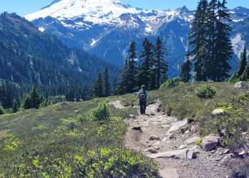 hiker on trail with dramatic mountain background