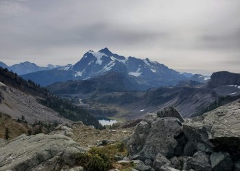 mountains under grey sky with small lake 