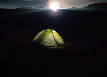 A tent glows from within at night.