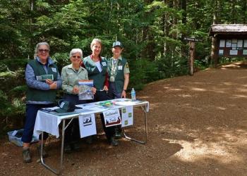 Four individuals at a table at a trailhead