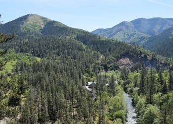 Mountains rise above a forested valley with a river passing below.