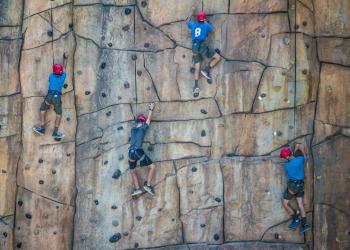 4 people using ropes to ascend climbing wall