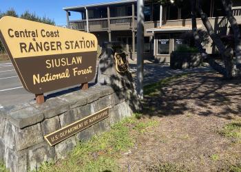 A sign that says "Central coast ranger station siuslaw national forest" in front of a building