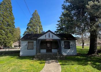 A white, wooden building with a stone porch leading to a doorway. Above the steps a sign reads, "Colliding Rivers Visitor Center."
