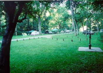 An open field with campsites and a fence boundary around the road and separate campsites. 