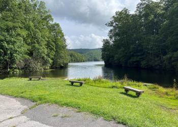 Three wooden benches in front of a mountain lake