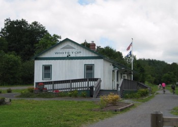 Whitetop visitor station with American flag in the front and a bike path alongside.