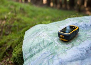 Forest map with GPS device laying on top
