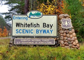 A forest service portal sign with the words Entering Whitefish Bay Scenic Byway