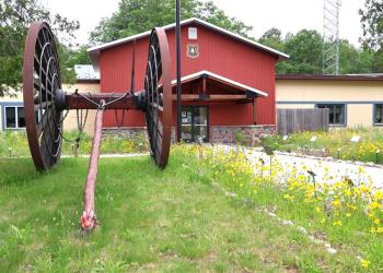 A Forest Service office painted red with a large wagon. 