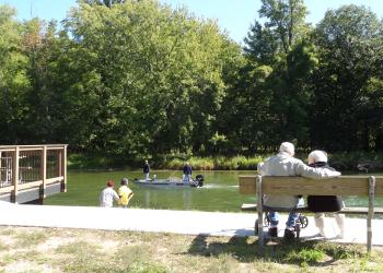 People recreating on a hiking path with a boat on the water in the background.